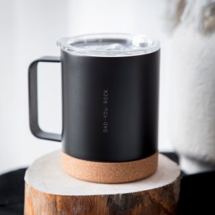 Caneca térmica de aço de dupla face, com base em cortiça. Disponível em branco e preto. A personalização é feita com gravação a laser.