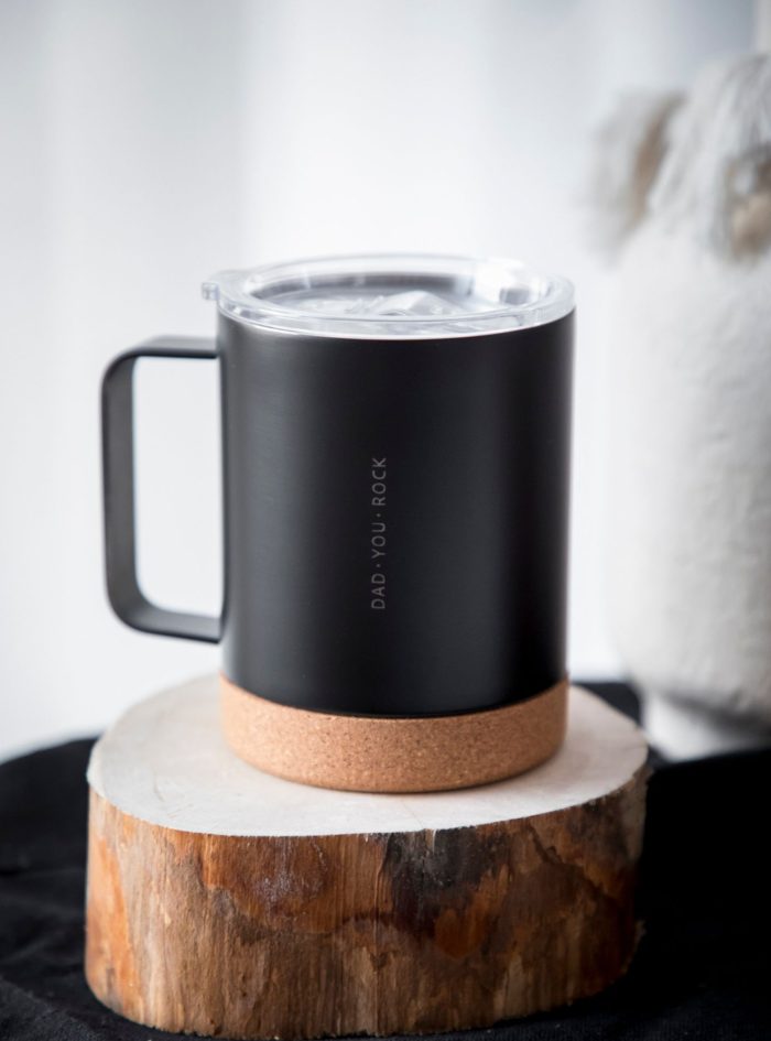 Caneca térmica de aço de dupla face, com base em cortiça. Disponível em branco e preto. A personalização é feita com gravação a laser.