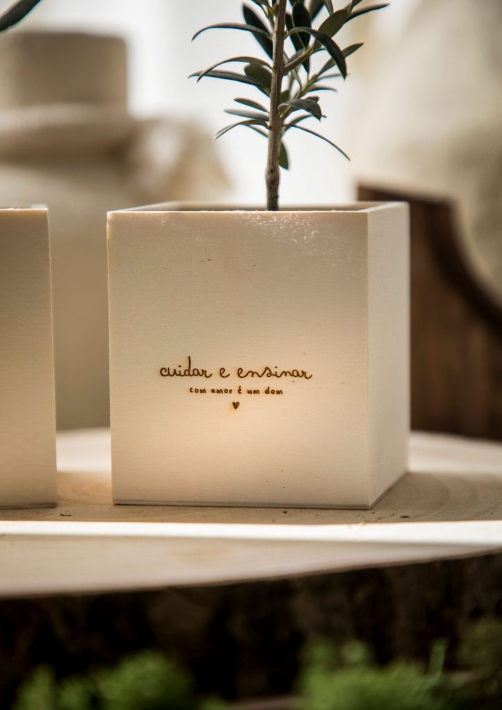 Oliveirinha em vaso de madeira com a personalização "cuidar e ensinar com amor é um dom"