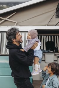 Pai radiante, a pegar na sua filha bebé ao colo, à beira do seu outro filho